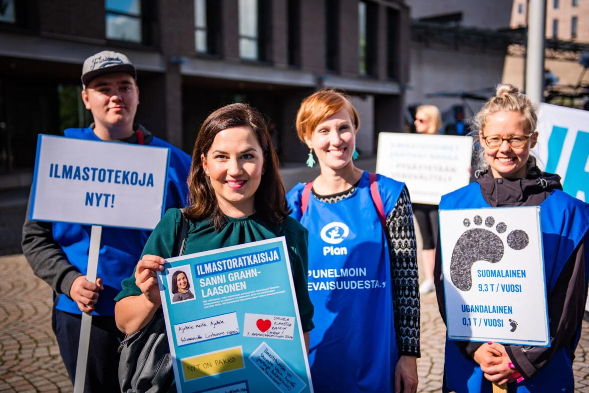 Planin liiveissä ja ilmastoaiheisissa kylteissä olevat Planin ilmastovaikuttajat poseeraavat yhdessä Sanni Grahn-Laasosen kanssa, joka pitelee saamaansa "ilmastoratkaisijat"-diplomia.